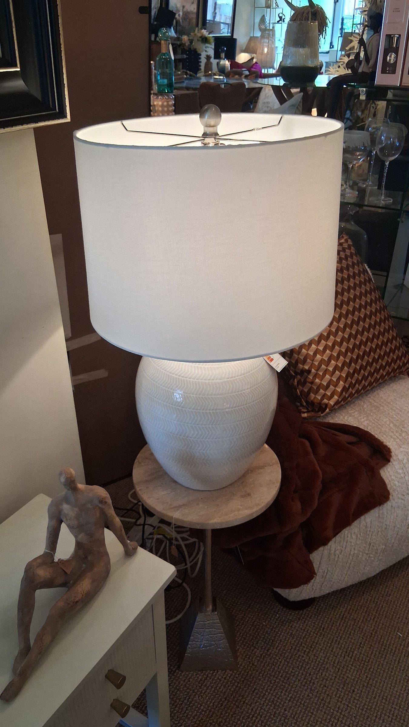 White ceramic table lamp with linen shade styled with bronze figurine